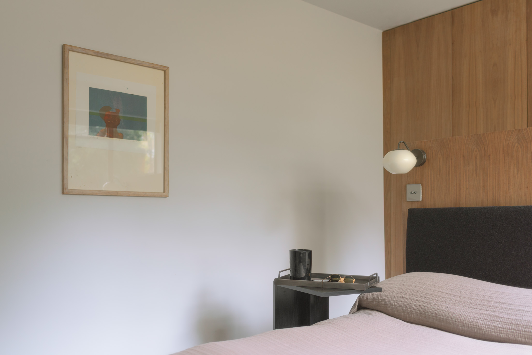 Walnut joinery, reading light and soft linen in the main bedroom